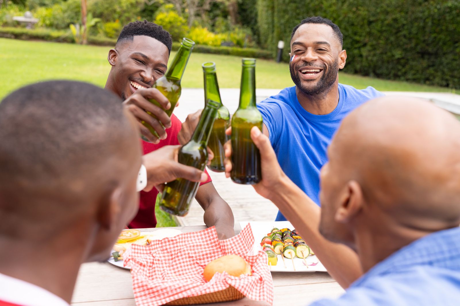 Friends raising cold beers at a backyard braai
